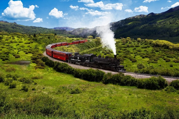 a train that is on a grassy hill