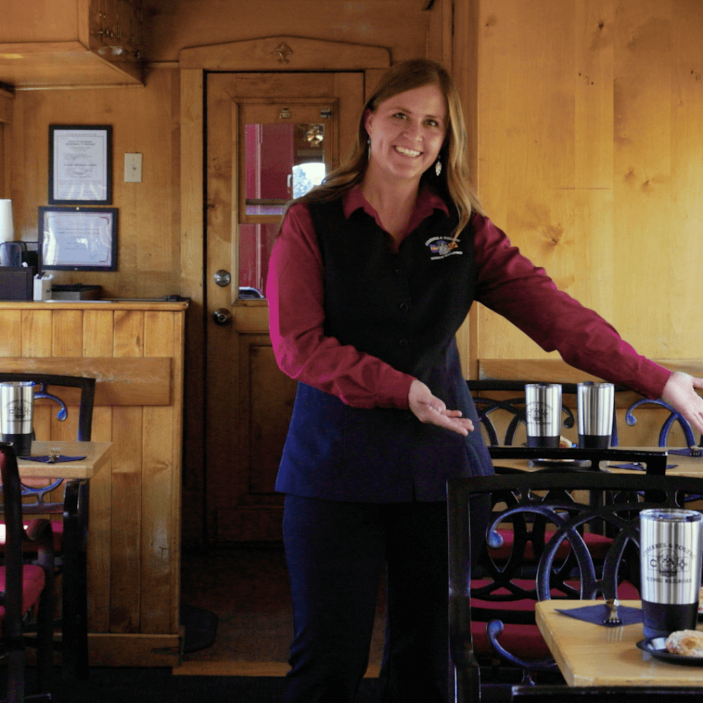 a train car attendant smiles and welcomes you.