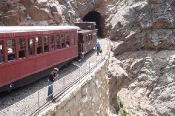 a train traveling down train tracks near a mountain