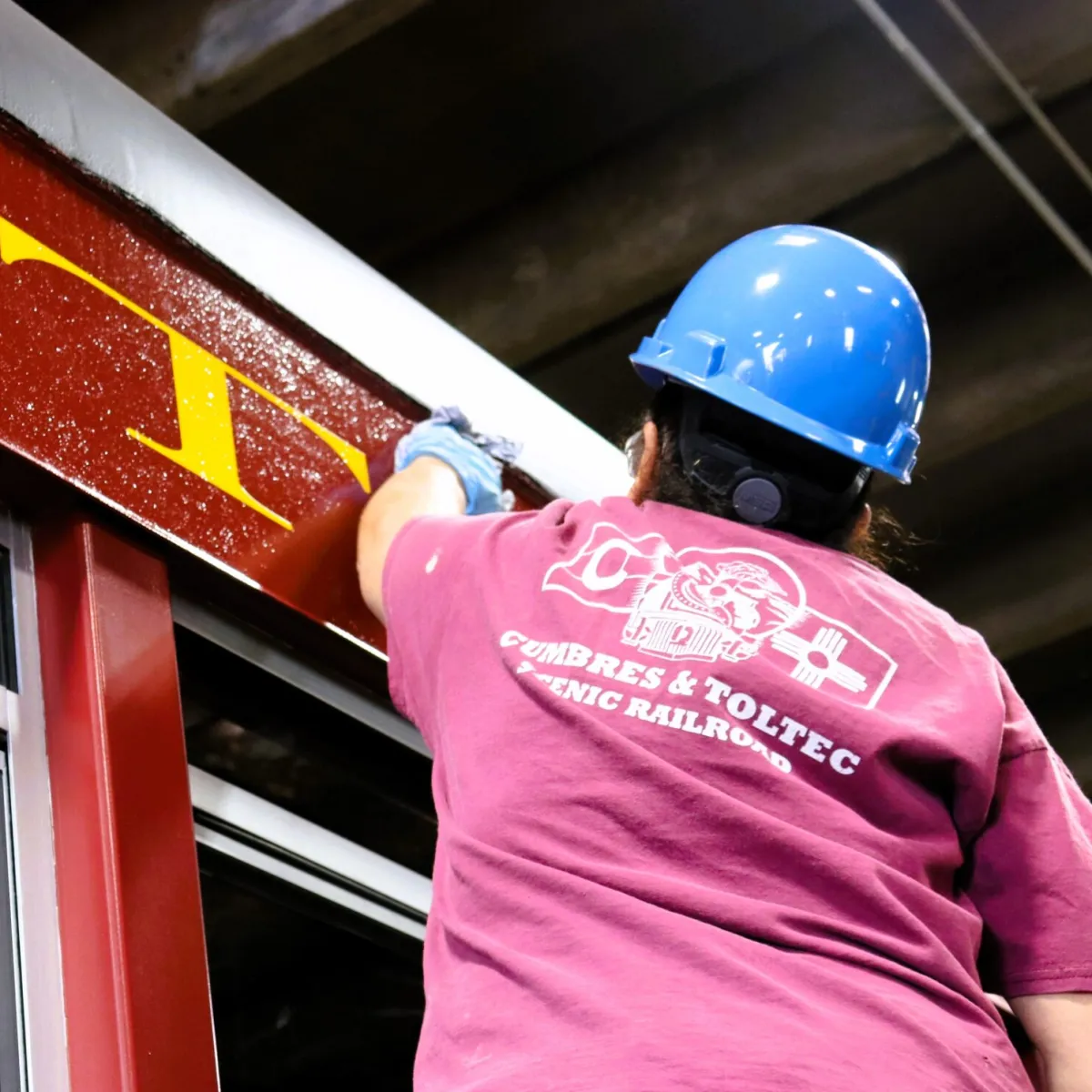 a person wearing a helmet cleaning a train car.