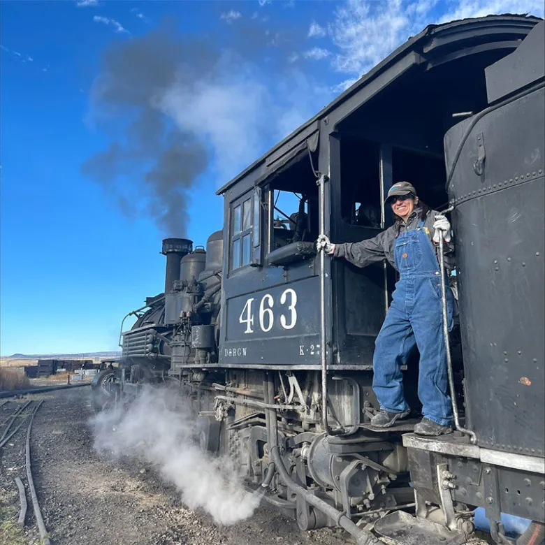 Employee in blue overalls on steam locomotive 463 on a clear day.