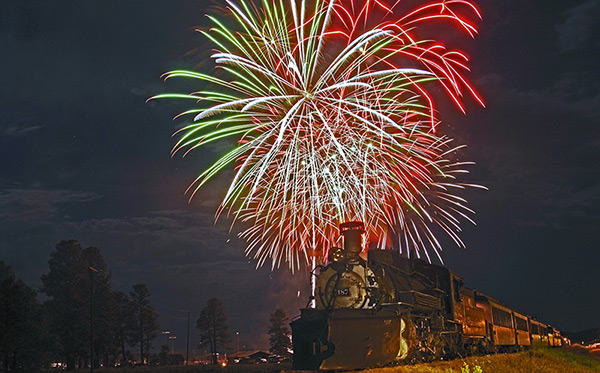 Old train with bright fireworks bursting above at night