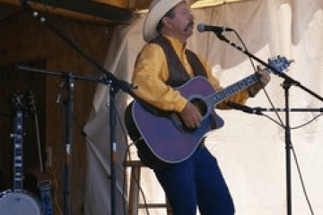 Fred Hargrove playing guitar and singing on stage.