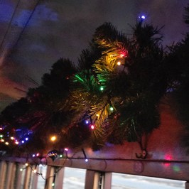 Festive lights and pine garland decorate a train interior.