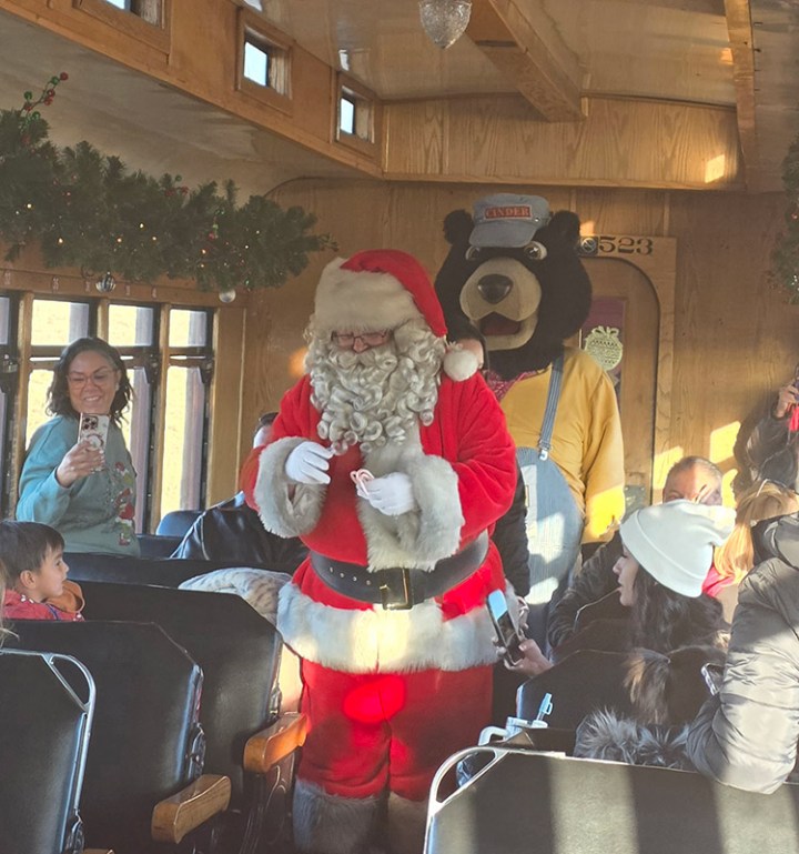Santa and a bear mascot entertain kids on a holiday train ride.