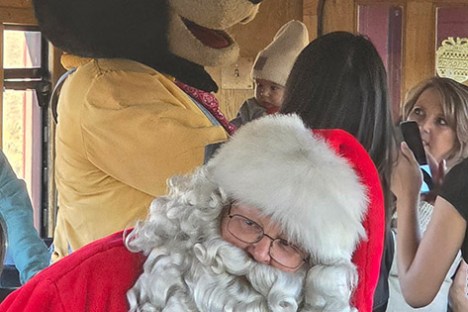 Santa and bear mascot interacting with children on a train.