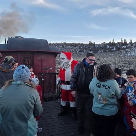 Santa Claus with people on a train platform in winter attire.