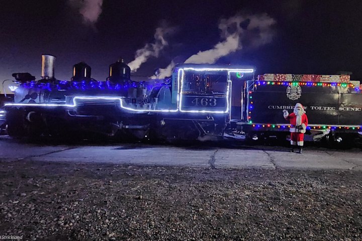 Steam train with festive lights and Santa Claus at night.