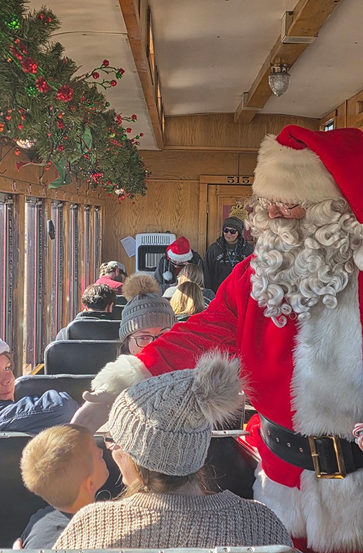 Santa Claus interacting with passengers on a festive train ride.
